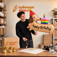 Jesse houdt de Teckel Happy Birthday XL Ballon vast in de warme inpakruimte van Ballonnenshop.nl.