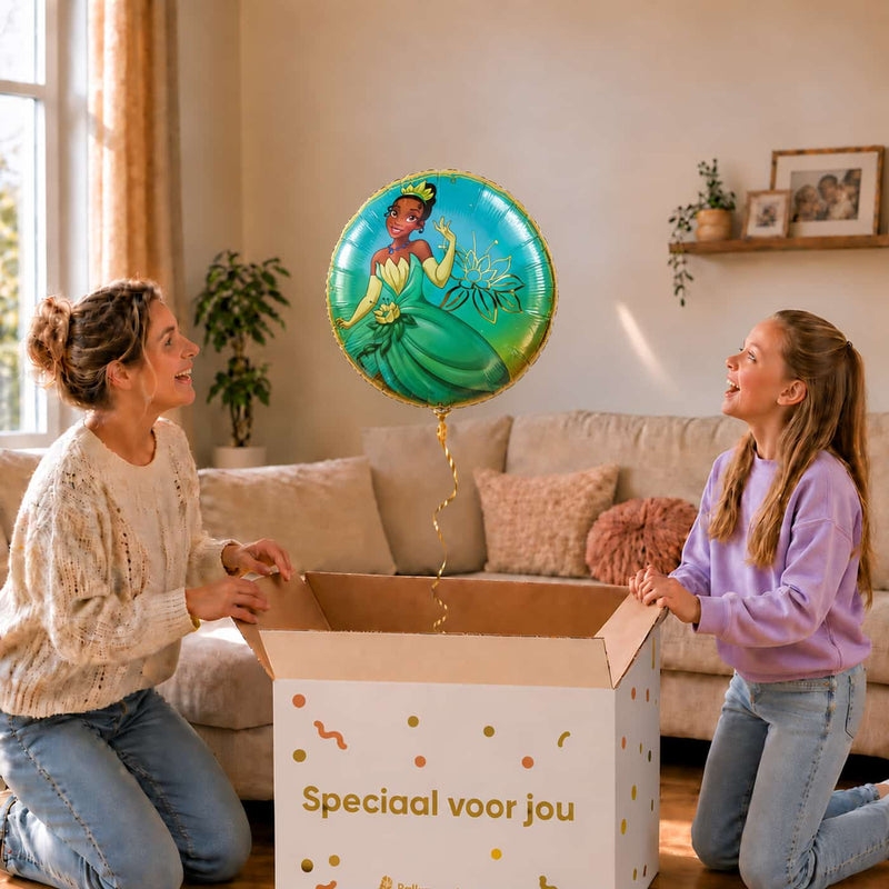 Moeder en meisje bekijken een Tiana Disney Prinses-heliumballon van 46 cm boven een geopende cadeaudoos.