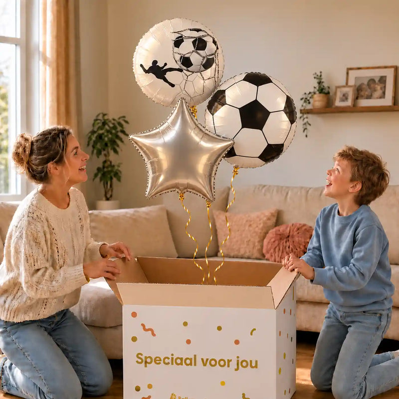 Voetbal Trosje Zilver/Wit/Zwart: moeder en zoon pakken het heliumgevulde ballonnentrosje uit een Speciaal voor jou-doos, met natuurlijk gekrulde gouden linten.