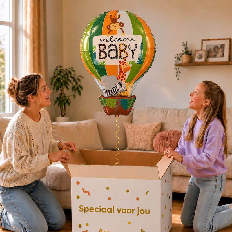 Welcome Baby Luchtballon Ballon zweeft boven een geopende cadeaudoos bij een moeder en meisje in een warme woonkamer.