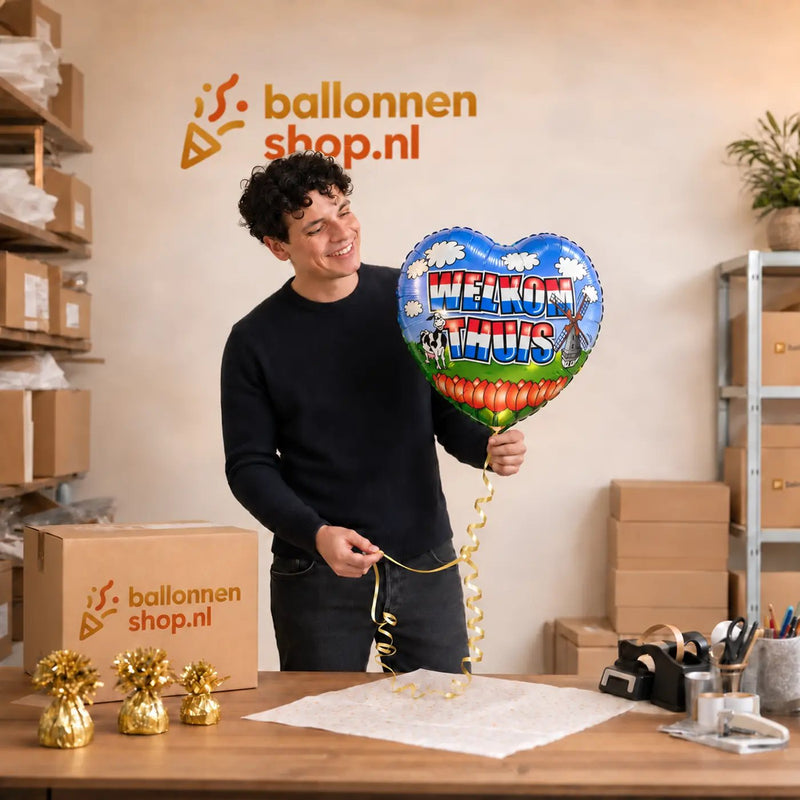 Jesse houdt de Welkom Thuis Helium Ballon vast in de warme werkplaats van Ballonnenshop.nl.
