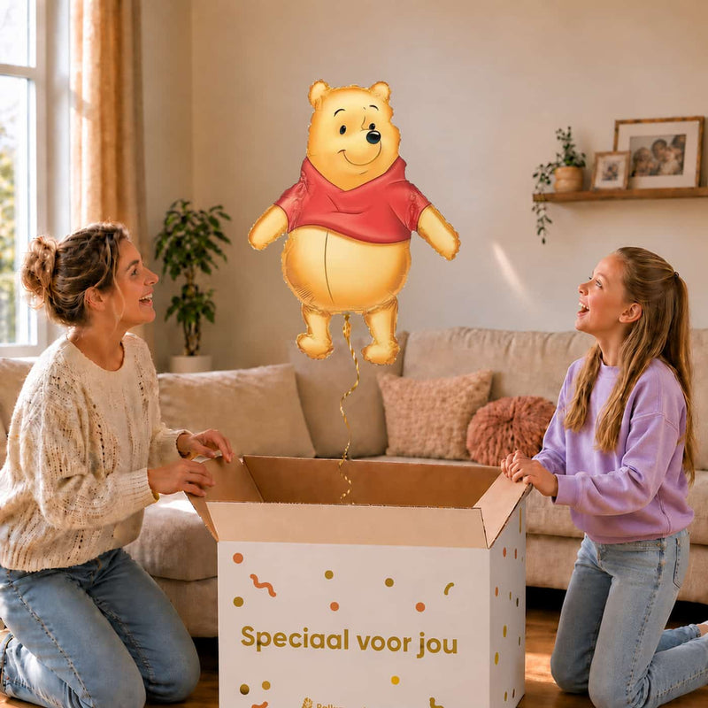 Moeder en meisje bekijken een Winnie de Poeh-ballon van 73 cm met gouden lint boven de geopende cadeaudoos ‘Speciaal voor jou’.