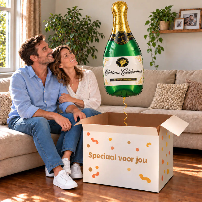 Een volwassen stel kijkt blij naar Champagne Fles Helium XL Ballon boven een grote Speciaal voor jou-doos in een warme woonkamer.